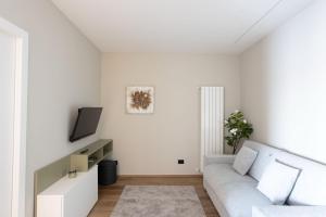 ein weißes Wohnzimmer mit einem Sofa und einem TV in der Unterkunft Profumo di LAGO - Il Lago incontra la tranquillità in Oggebio