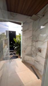 une salle de bains avec des murs en marbre blanc et une porte ouverte dans l'établissement Villa Guarumo, à Santa Eulalia