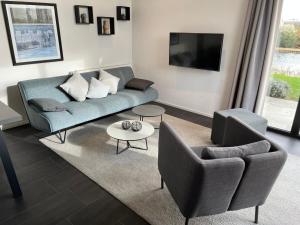 a living room with a couch and chairs and a tv at Ferienhaus 55 am Wasser Olburgen - perfekt für Familien - mit Freibad, Sauna, Restaurant und Spielplatz in Olburgen +115 photos