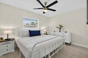 a white bedroom with a bed with a ceiling fan at Sunset Beach Suites Unit 3 in St. Pete Beach