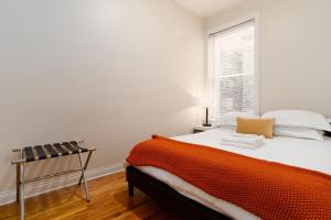 an orange and white bed in a room with a window at Flexhome Wicker Park - Stylish 2BR - Sleeps 6 in Chicago
