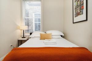 an orange and white bed in a room with a window at Flexhome Wicker Park - Stylish 2BR - Sleeps 6 in Chicago