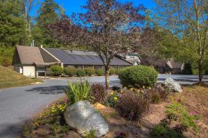 una casa con un albero e dei fiori in strada di Stoney Brook Cottage at Echota a Boone