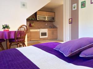 a bedroom with a purple bed and a kitchen at Apartment Pohorje in Maribor