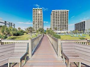Un paseo marítimo de madera con bancos y dos edificios altos. en 10th Floor Oceanfront with Spectacular Views Pool, en Myrtle Beach