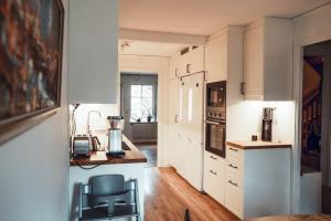 SolsidanにあるStylish Townhouse Near Stockholm Natureの白いキャビネット、テーブル、椅子付きのキッチン