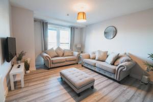 a living room with two couches and a tv at Top-Floor 2-Bed Near Braehead in Renfrew