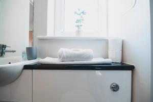 a bathroom with a sink and a towel on a counter at Top-Floor 2-Bed Near Braehead in Renfrew +20 photos