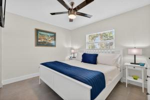 a white bedroom with a bed with a blue blanket at Sunset Beach Suites Unit 9 in St Pete Beach