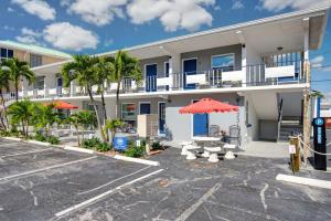 a building with a red umbrella and benches and palm trees at Sunset Beach Suites Unit 6 in St. Pete Beach