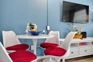 a dining room with a white table and red chairs at Sunset Beach Suites Unit 6 in St. Pete Beach