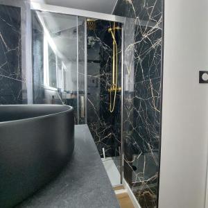 ein Bad mit einer schwarzen und goldenen Marmorwand in der Unterkunft Le contemporain Centre historique in Langres