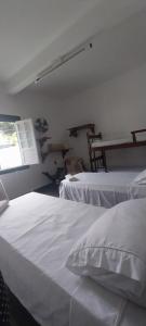 two white beds in a room with a window at Quartos Sierra Tiradentes in Tiradentes +3 photos