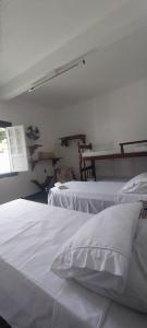 a bedroom with two beds with white sheets and a window at Quartos Sierra Tiradentes in Tiradentes