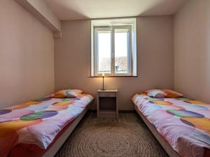 - 2 lits dans une chambre avec une table et une fenêtre dans l'établissement Charmante maison avec jardin, proche de George Sand, circuit auto, hippodrome, plans d'eau et nature. - FR-1-591-320, à Thevet-Saint-Julien