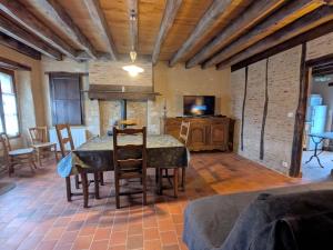 une salle à manger avec une table et des chaises et une télévision dans l'établissement Maison de Caractère Rénovée avec Jardin, Terrasse, et Proche du Château Guillaume - FR-1-591-131, à Lignac