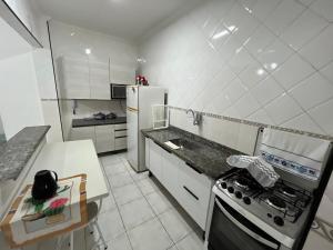 a white kitchen with a stove and a refrigerator at Apartamento Praia Grande 300 m da praia in Praia Grande