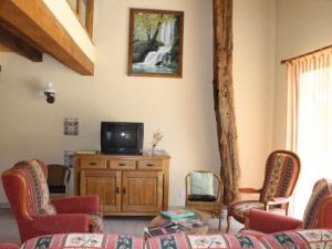 Ein Wohnzimmer mit Stühlen und einem Fernseher auf einem Holzschrank. in der Unterkunft Gîte de charme avec cheminée, terrasse et garage à Brixey-aux-Chanoines - FR-1-585-10 in Brixey-aux-Chanoines