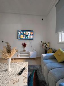a living room with a couch and a tv on the wall at Séjour détente près plage des nations in Sale +3 photos