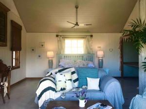 een slaapkamer met een blauw bed met kussens erop bij Bay of Islands - Vineyard Cottage, chic private stunning view in Purerua