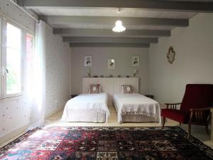 une chambre avec deux lits et une chaise rouge dans l'établissement Ferme du XIXe avec cheminée, près des gorges du Doulon - FR-1-582-227, à Frugières-le-Pin