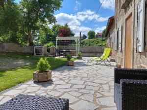 un patio avec une chaise jaune et un bâtiment dans l'établissement Maison de charme restaurée au bord d'un ruisseau avec terrasse, proche activités de plein air et confort moderne - FR-1-582-225, à Chaylot