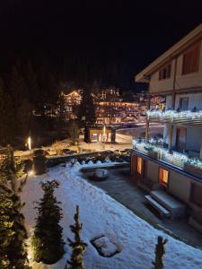 a night view of a building with snow and lights at Apt Design a Campiglio 400m funivie in Madonna di Campiglio