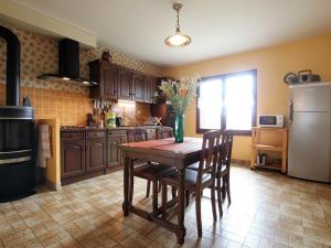 une cuisine avec une table en bois et un réfrigérateur dans l'établissement Ferme du XIXe avec cheminée, près des gorges du Doulon - FR-1-582-227, à Frugières-le-Pin