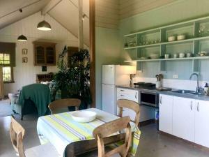 een keuken met een tafel en stoelen in een kamer bij Bay of Islands - Vineyard Cottage, chic private stunning view in Purerua +57 foto's