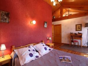 a bedroom with a bed with a red wall at Gîte en pierre avec terrasses, proche de sites médiévaux, idéal pour famille avec équipements bébé. - FR-1-582-256 in Boisset