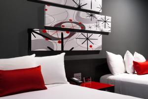 Astro Pasadena Hotel في باسادينا: غرفة بسريرين ومخدات حمراء وبيضاء