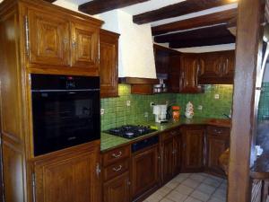 eine Küche mit Holzschränken und einem Herd mit Backofen in der Unterkunft Gîte Confortable au Cœur du Vignoble de Sancerre avec Internet et Proche de la Loire à Vélo - FR-1-586-3 in Sury-en-Vaux + 2 Fotos