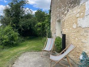 2 chaises assises à l'extérieur d'un bâtiment en pierre dans l'établissement Échappez-vous à la campagne sarthoise: charme, nature, proximité 24H du Mans & zoo! - FR-1-410-448, à Mayet