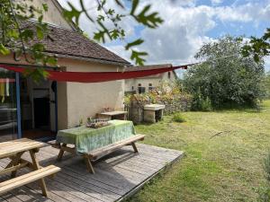 a table and benches on a wooden deck next to a house at Maison typique en Berry avec jardin privatif, BBQ et parking - FR-1-591-598 in Thenay