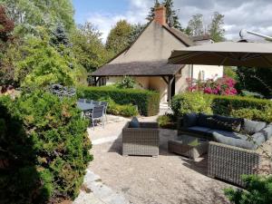 une terrasse avec un parasol, des chaises et des buissons dans l'établissement Gîte haut de gamme près de l'Abbaye de Noirlac - Séjour tout confort avec jardin et terrasses - FR-1-586-13, à Bruère-Allichamps