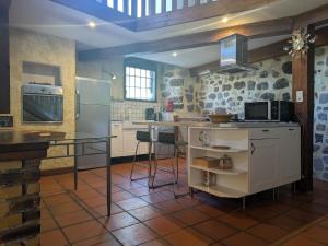 a kitchen with a refrigerator and a counter with stools at Élégante maison de maître XVIIIe, jardin clos 500m², nature, proche Puy-en-Velay, 11 pers., cosy & confort - FR-1-582-315 in Arsac-en-Velay +15 photos