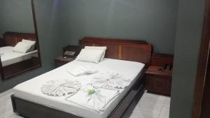 een slaapkamer met een bed met witte lakens en een spiegel bij Hotel Porto Calem in Sao Paulo +4 foto's