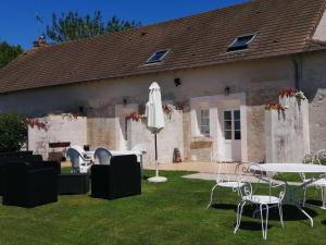a house with a table and chairs and an umbrella at Ancienne ferme avec jardin, trampoline et pétanque entre Valençay et Beauval - FR-1-591-217 in Frédillé