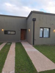 a gray building with a door and a grass yard at Casa Clara in Tandil