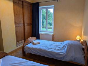 a bedroom with two beds and a window at Gîte calme en forêt, proche Gien, 3 chambres et 2 salles d'eau - FR-1-590-555 in Ouzouer-sur-Trézée