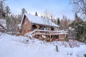 Une grande maison en bois recouverte de neige dans l'établissement Sous Bois & Loft - Hot tub - Ski out, à Saint-Faustin–Lac-Carré