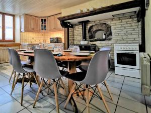 une grande cuisine avec une table et des chaises en bois dans l'établissement Maison de bourg restaurée avec cour privative au coeur d'un village paisible, proche gorges de l'Allier et sites historiques - FR-1-582-220, à Mazeyrat-Aurouze 4 autres photos