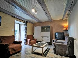 un salon avec deux chaises et une télévision dans l'établissement Maison de bourg restaurée avec cour privative au coeur d'un village paisible, proche gorges de l'Allier et sites historiques - FR-1-582-220, à Mazeyrat-Aurouze