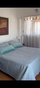 a bedroom with a large bed with blue pillows at Departamento frente al mar 3 ambientes Playas de Surf in Mar del Plata