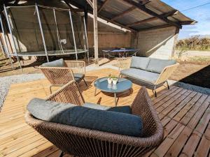 eine Terrasse mit Korbstühlen und einem Tisch auf einem Holzdeck in der Unterkunft Deux maisons berrichonnes avec jardin privatif et cour partagée, idéale pour les groupes - FR-1-591-617 in Thenay