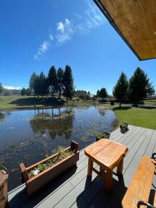 a wooden deck with a table and a lake at Wau Purul, Cabaña 2 in Cholila