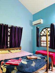 a bedroom with a bed with purple walls and a window at Mayelle Agonda in Agonda +11 photos