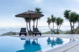 una piscina con dos tumbonas y una sombrilla y palmeras en Prosili, en Aiándion