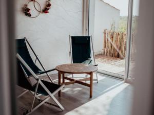 - deux chaises et une table sur une terrasse couverte dans l'établissement Gîte 4 chambres avec bien-être et terrasses au cœur du Marais Breton - FR-1-426-559, à Bois-de-Cené
