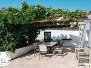 un patio avec une table et des chaises sous une pergola dans l'établissement Gîte 4 chambres avec bien-être et terrasses au cœur du Marais Breton - FR-1-426-559, à Bois-de-Cené 23 autres photos